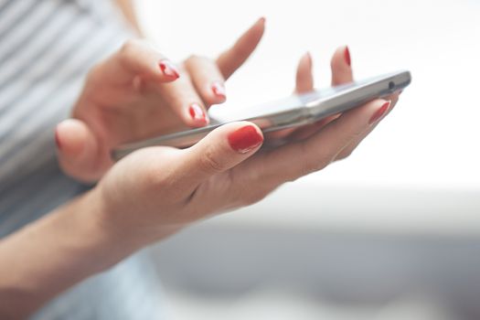 Woman with red manicure using smartphone. Horizontal photo