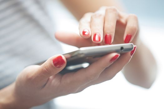 Woman with red manicure using smartphone. Horizontal photo