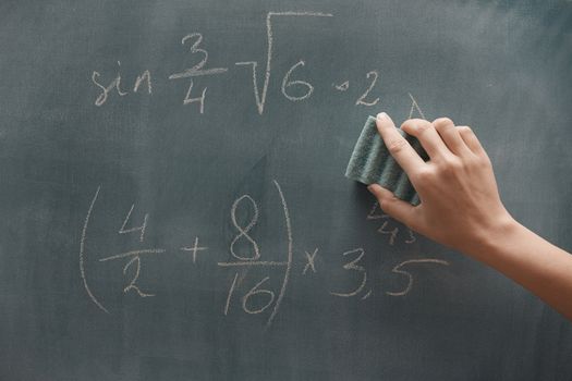 Hand of student studying mathematics and writing on a blackbroard