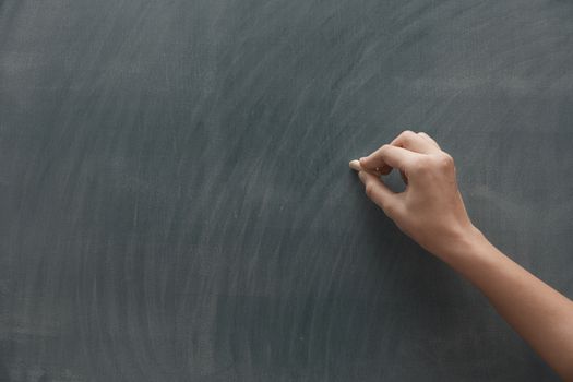 Human hand with chalk at the blackboard