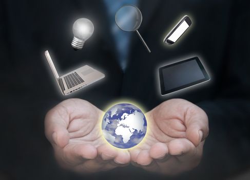 Business man with a laptop, tablet, mobile phone and various work related devices spinning around a globe 