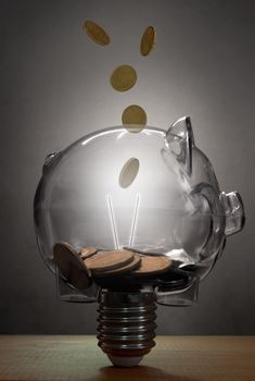Money falling into a glass light bulb in the shape of a piggybank 