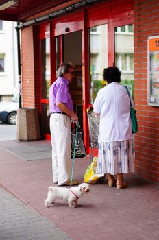 POZNAN, POLAND - SEPTEMBER 13, 2014: Man and woman standing with dog in front of a supermarket