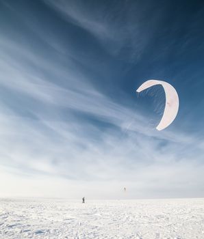 Kite surfer being pulled by his kite across the snow