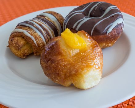 In the pictured three pastries served on a white plate .