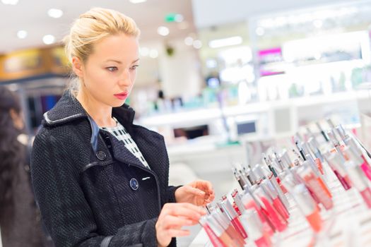 Beautiful blond lady testing  and buying cosmetics in a beauty store.