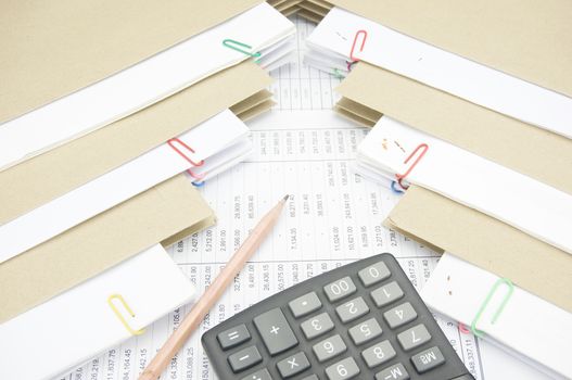 Pencil and calculator between stack paperwork report of sales and receipt with envelope on finance account.