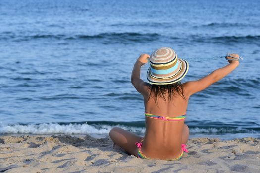 Little girl on the beach at sunset, with her hands she holds a pearls necklace.
