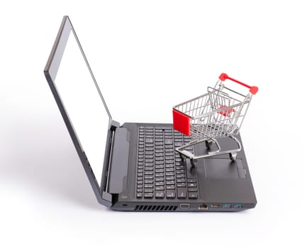 Shopping cart on laptop on isolated white background, side view