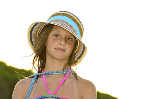 Little girl on the beach at sunset, portrait smiling with a large hat.