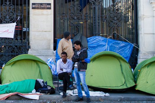 FRANCE, Paris: Two refugees wait in front of the city hall of the 18th arrondissement in Paris, on September, 15, 2015. Almost hundred and fifty refugees from South Soudan and Eritrea camp in front of the city hall of the 18th arrondissement in Paris since September, 4, 2015. Paris mayor Anne Hidalgo announced on September, 15, 2015 giving them a place in one of the seven installations opened in the capital and around las week. 