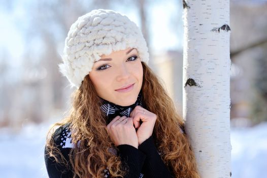 beautiful girl stands near the birch in winter