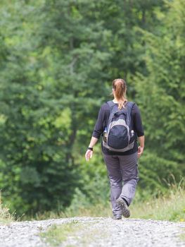 Hiker, young woman with backpack walking on footpath, Switzerland