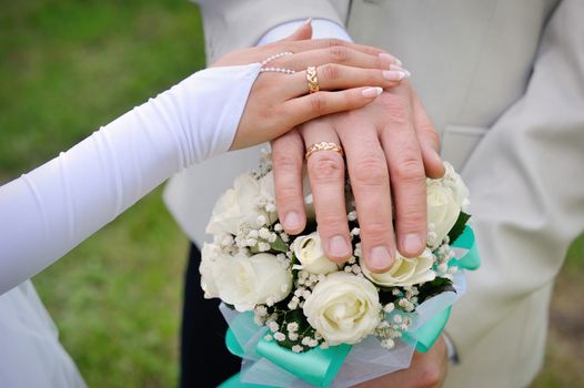 hand the bride and groom with rings on wedding bouquet