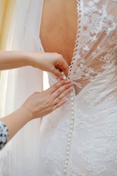 closeup portrait of a maid of honor helping the bride with her dress