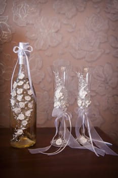 Decorated wedding glasses and bottle of champagne