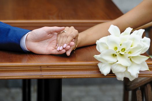 bride holding the groom's hand and wedding bouquet
