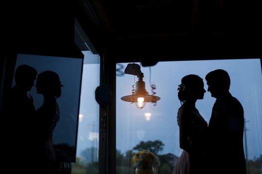 silhouettes of the bride and groom on the background of the window