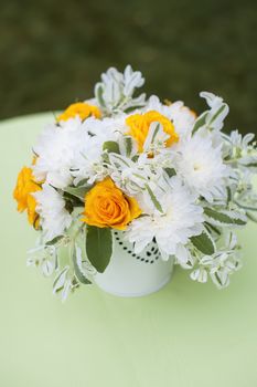 Beautiful bouquet of bright flowers in white vase,  on bright background