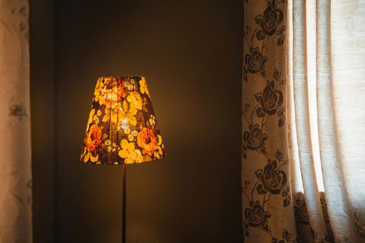 vintage Bedroom floor lamp glowing orange in a corner of a room 