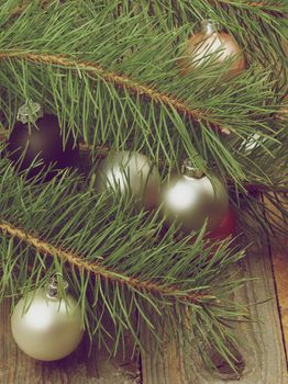 Christmas Decoration with Solver, Black and Pink Baubles into Fluffy Green Pine Branches closeup on Rustic Wooden background. Retro Styled