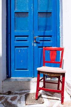 Detail of rustic colorful blue door and red wooden chair