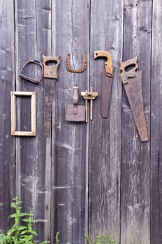 Antique handicraft tools and horseshoe hanging on old wooden barn wall