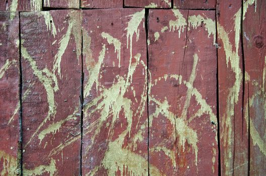 Golden paint on red wooden old barn wall background