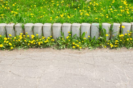 Stone barrier with grass and yellow flowers
