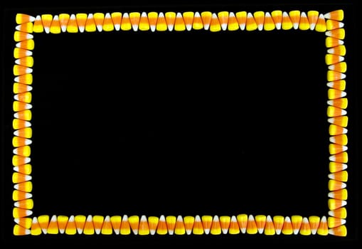 Brightly colored border made from candy corn on a black background.  Lots of copy space.
