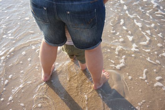 Adult and child legs on beach sand