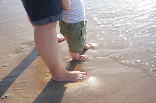 Adult and child legs on beach sand