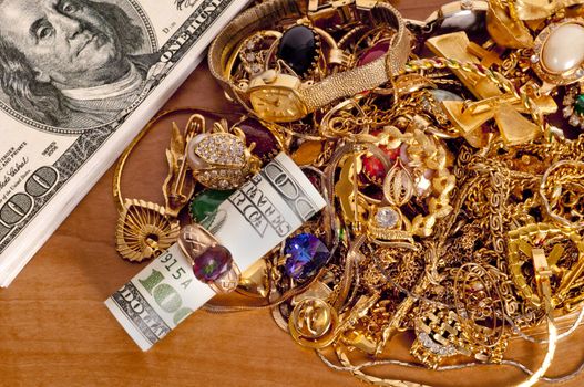 Great concept showing how you can make money by selling your gold jewelry. Cash rolled up inside a ring on top of pile of gold
