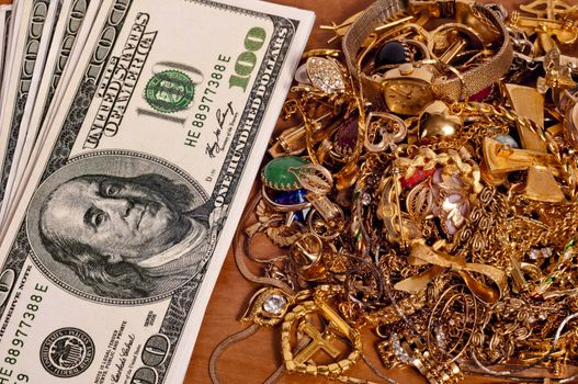 Horizontal shot of lots of cash next to a pile of jewelry.  Concept of selling your gold jewelry for big bucks.