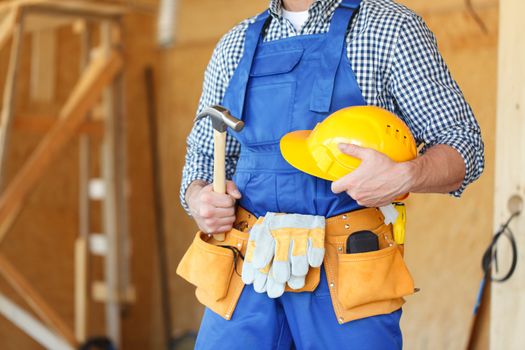 Construction worker with helmet and hammer in new wooden house