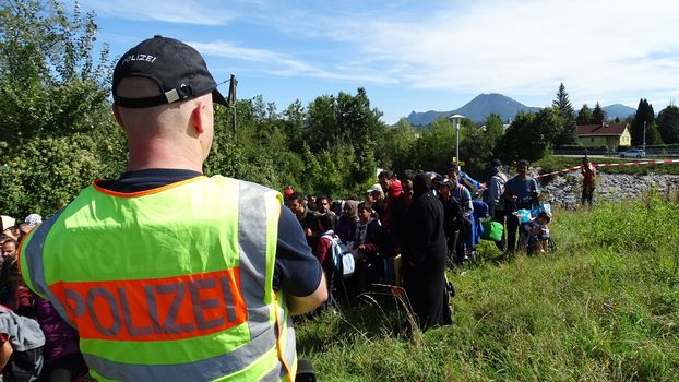 GERMANY, Freilassing: A German policeman watches over refugees at the gates of Freilassing, Bavaria, on the German side of the Germany-Austria border, September 16, 2015.