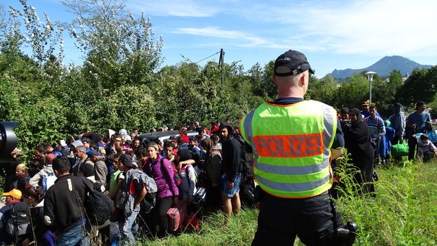 GERMANY, Freilassing: A German policeman watches over refugees at the gates of Freilassing, Bavaria, on the German side of the Germany-Austria border, September 16, 2015.