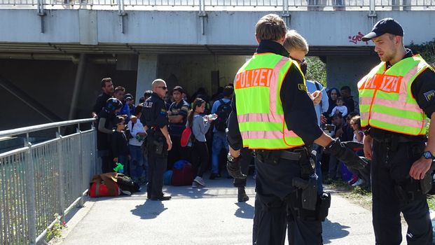 GERMANY, Freilassing: Refugees wait at the gates of Freilassing, Bavaria, on the German side of the Germany-Austria border, as German police confer, September 16, 2015.