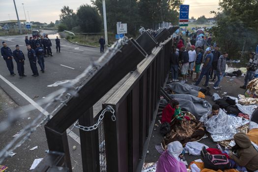 SERBIA, Horgos: Refugees wait at the Serbia-Hungary border, blocking traffic, as Hungarian border gurads look on, after Hungary closed the border crossing on September 16, 2015.****Restriction: Photo is not to be sold in Russia or Asia****