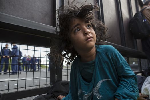 SERBIA, Horgos: A refugee child wakes up behind a border fence as Hungarian border guards appear in the background at the Serbia-Hungary border after Hungary closed the border crossing on September 16, 2015.****Restriction: Photo is not to be sold in Russia or Asia****