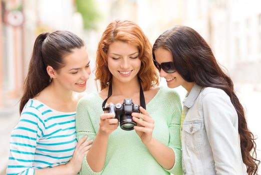 tourism, travel, leisure, holidays and friendship concept - smiling teenage girls with camera outdoors