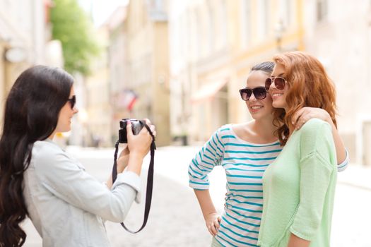 tourism, travel, leisure, holidays and friendship concept - smiling teenage girls with camera outdoors