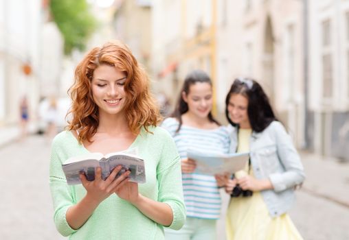 tourism, travel, holidays and friendship concept - smiling teenage girls with city guide, map and camera outdoors
