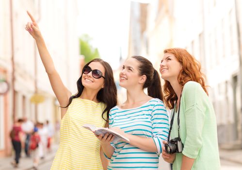 tourism, travel, leisure, holidays and friendship concept - smiling teenage girls with city guide and camera outdoors