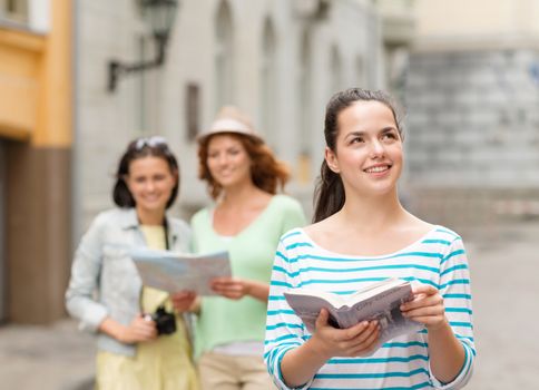 tourism, travel, holidays and friendship concept - smiling teenage girls with city guide, map and camera outdoors