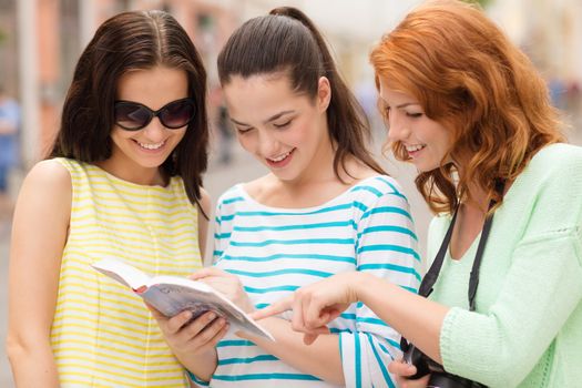 tourism, travel, leisure, holidays and friendship concept - smiling teenage girls with city guide and camera outdoors