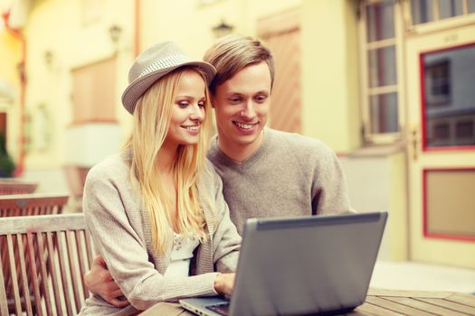 summer holidays, city, dating and technology concept - smiling couple with laptop computer in cafe