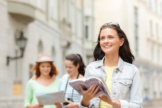 tourism, travel, holidays and friendship concept - smiling teenage girls with city guide, map and camera outdoors