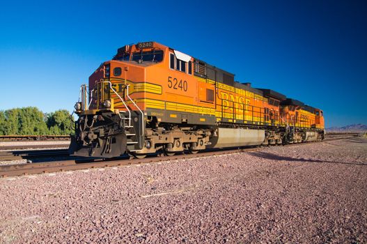 Distinctive orange and yellow Burlington Northern Santa Fe Locomotive freight train No. 5240 on the tracks at the town of Needles, California. Photo taken on February 5 2013.