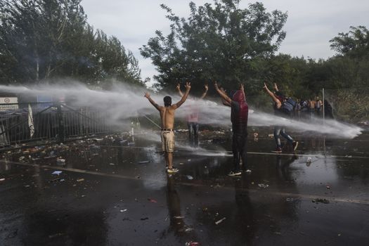 SERBIA, Horgos: Refugees stand defiant as Hungarian police fire tear gas and water cannons into the refugees in the Serbian border town of Horgos on September 16, 2015, after Hungary closed its border in an effort to stem the wave of refugees entering the country. 